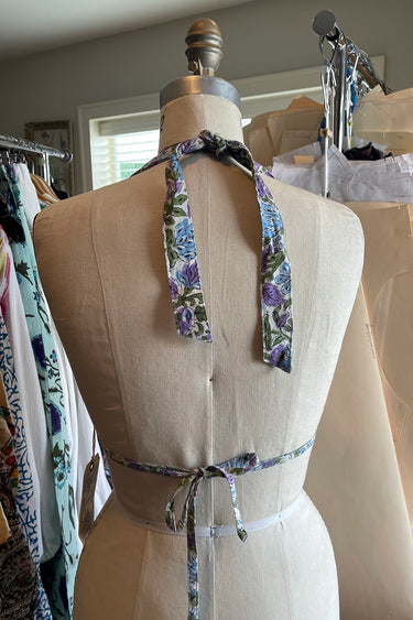 A floral printed bikini top with ties around the neck and back, displayed on dress form, back view.
