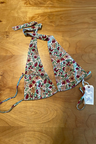 A halter style bikini top with a floral pattern in red and green on an ecru background, displayed on a flat surface.