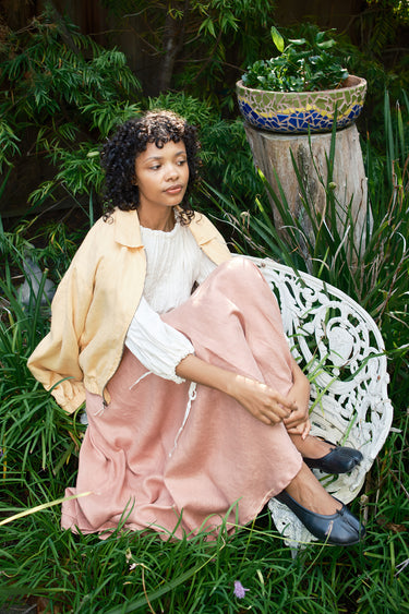 Woman sitting on a white bench in a garden setting