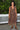 A woman wearing a raisin floral tapestry wrap dress with elastic neckline and pockets, standing outdoors.