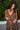 A woman wearing a raisin floral tapestry wrap dress with elastic neckline and pockets, standing outdoors.
