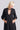 A woman standing in a white wall photo studio wearing a 3/4 sleeve midi jet black caftan.