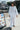 A woman standing outside at the beach wearing white full leg trousers with a matching mini dress over them.