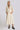 A woman standing in a white wall photo studio wearing a 3/4 sleeve midi alabaster off white caftan.