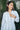 A woman outside wearing a long sleeved white with black stripe gauze shirt jacket.