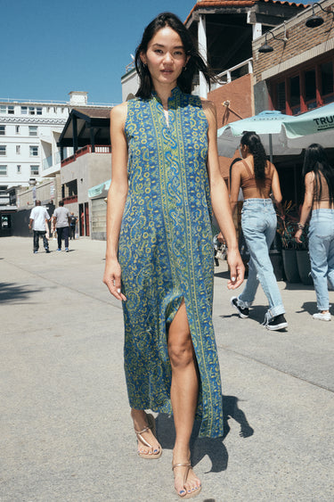 A woman on a beach boardwalk wearing a sheath dress made from a dark blue paisley tapestry.