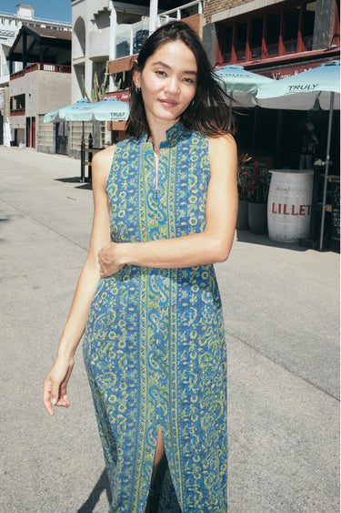 A woman on a beach boardwalk wearing a sheath dress made from a dark blue paisley tapestry.