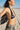 Woman in a black and white patterned bikini on a sandy beach with palm trees in the background.