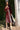 Woman in a burgundy dress standing next to a palm tree