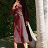 Woman in a burgundy dress standing next to a palm tree