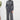 Woman wearing a gray jumpsuit standing against a white wall.