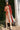 Woman in a persimmon dress standing next to palm trees