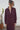 Woman wearing a balck fig outfit standing next to a potted plant against a textured wall.