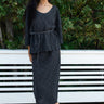 model wearing coal black lace skirt and top standing in front of greenery