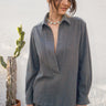 Woman wearing a gray long-sleeve top with a cactus plant in the background