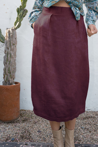 Person wearing a burgundy skirt with a cactus plant in the background