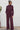 Woman wearing a black fig jumpsuit standing against a white wall.