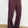 Person wearing black fig flared pants against a white wall.