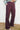 Person wearing black fig flared pants against a white wall.