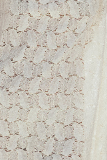 Close-up of a ecru textured lace fabric with a geometric pattern