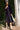 Woman in a jet black dress standing next to a palm tree