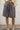 Person wearing gray shorts and beige boots against a white wall.