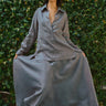 woman wearing pewter skirt and blouse standing in front of greenery 