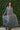 woman wearing pewter skirt and blouse standing in front of greenery 