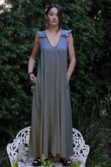 Woman wearing a pewter dress with a sta on a white chair outdoors.