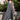 Woman wearing a gray sleeveless dress standing outdoors with greenery in the background