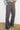 Person wearing gray flared pants against a white wall.