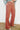 Person wearing a persimmon flared pants against a white wall.
