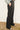 Person wearing black wide-leg pants with a patterned shirt in the background