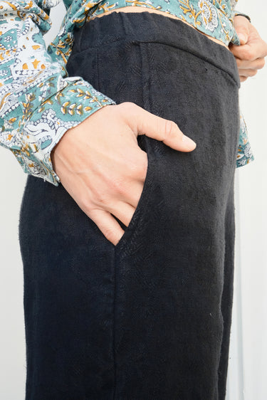 Person wearing black pants with a floral-patterned shirt.