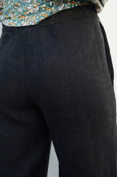 Close-up of dark pants with a floral patterned garment at the top corner.