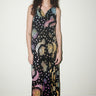 Woman wearing a long, sleeveless dress with celestial pattern against a plain background