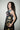 Woman wearing a black sleeveless dress with celestial pattern against a plain background