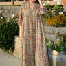 A woman standing outside wearing a beige ground with red and brown floral vintage rose tapestry caftan.