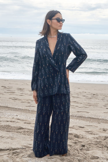 Woman at the beach wearing an ikat double breasted jacket with matching trousers.