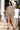 Woman in a floral outfit standing on steps outside a house