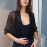 Woman standing a door way wearing a black zero waste lace shrug over a black tank top, paired with an ikat maxi skirt.