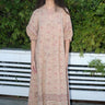 A woman standing outdoors wearing a blush maxi dress with floral hand block print design, featuring balloon sleeves and wide elastic at the cuffs.