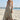 Woman in a floral dress standing on a beach with a pier in the background