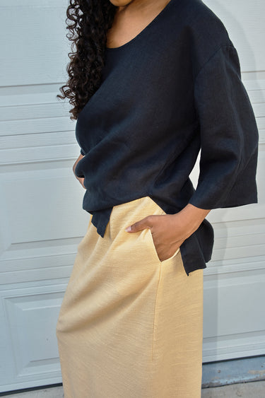 Person wearing a black top and yellow skirt against a light gray background