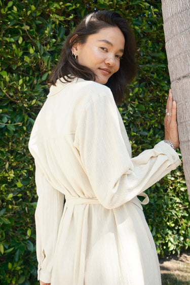 A woman standing outdoors wearing an alabaster midi shirt dress with long sleeves and an obi belt.