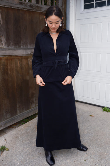 A woman wearing an ebony black  corduroy shirt with long sleeves and an obi belt.
