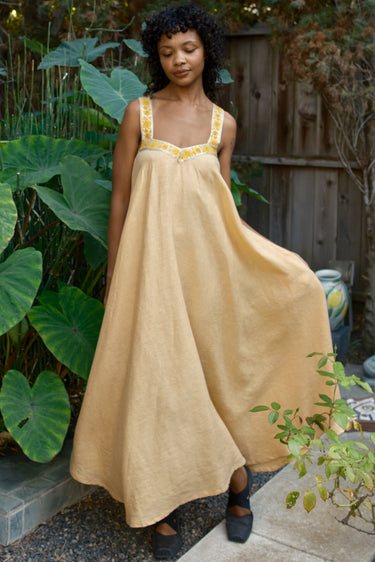 Woman wearing a long yellow dress with yellow accents in a garden setting