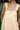 yellow dress with yellow floral ribbon straps against a blurred green background