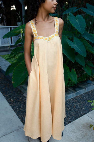 Woman wearing a yellow  dress with yellow ribbon in an outdoor setting