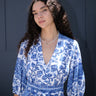 A woman wearing a blue and white floral caftan with three quarter balloon sleeves and an obi belt.